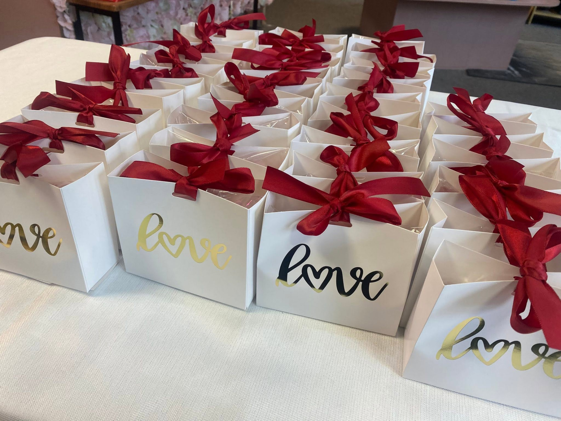 White gift boxes with red ribbons and gold love lettering