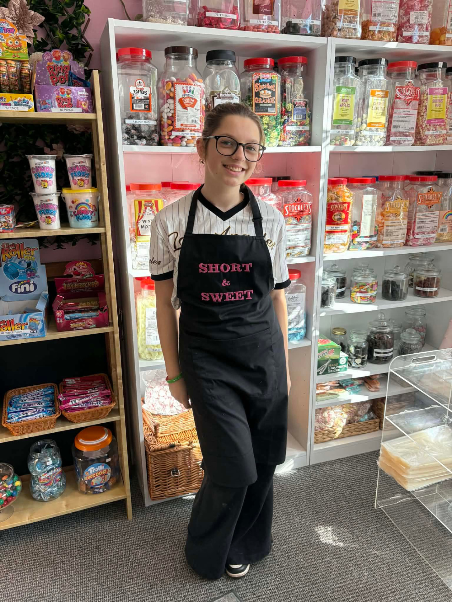 Team member in a Short & Sweet apron in front of shelves of traditional sweet jars